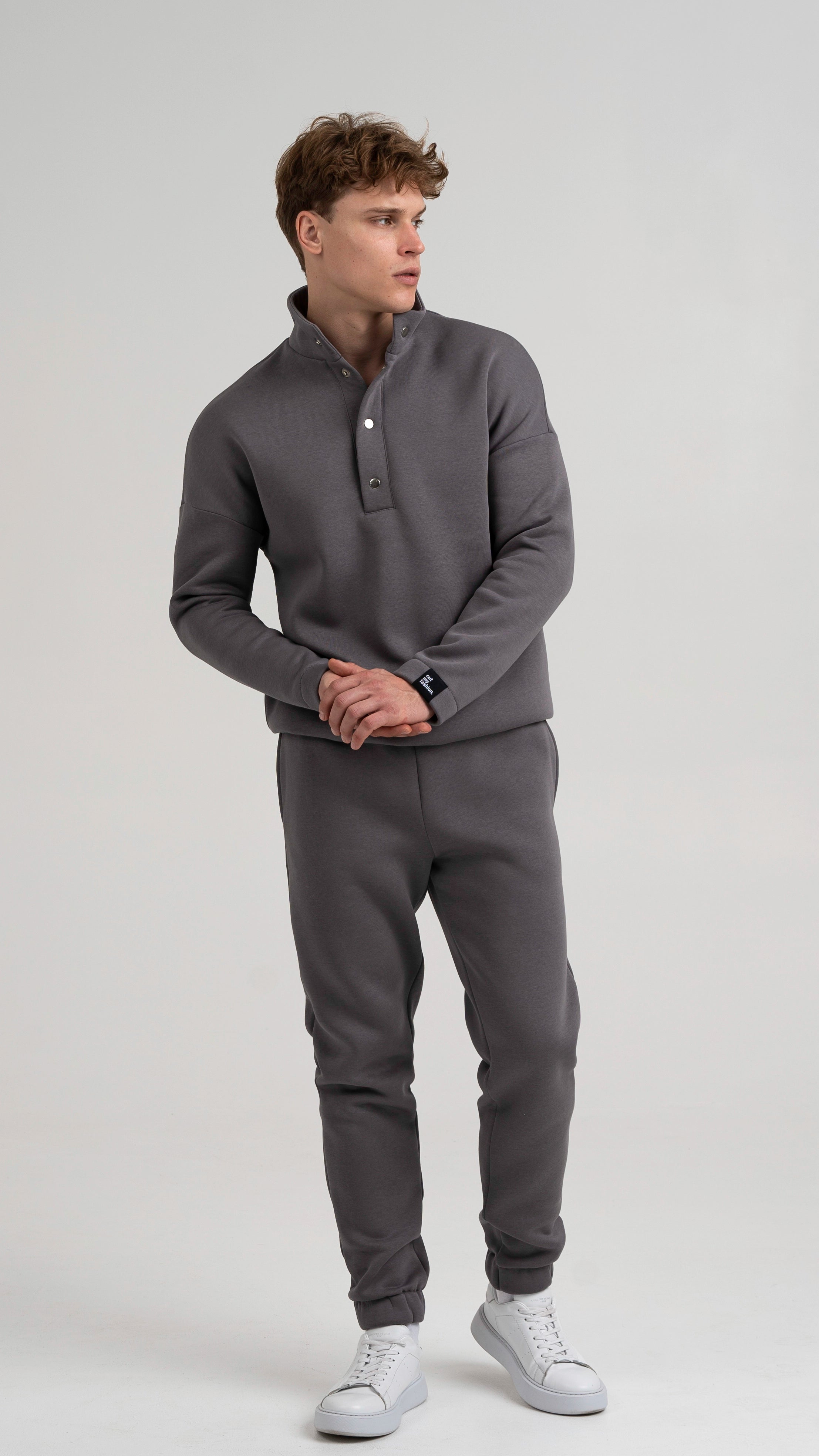 Vyras vilki cutmyfashion pilkos spalvos treningus su pūkeliu ir sagomis, stovintis žvelgia į šoną