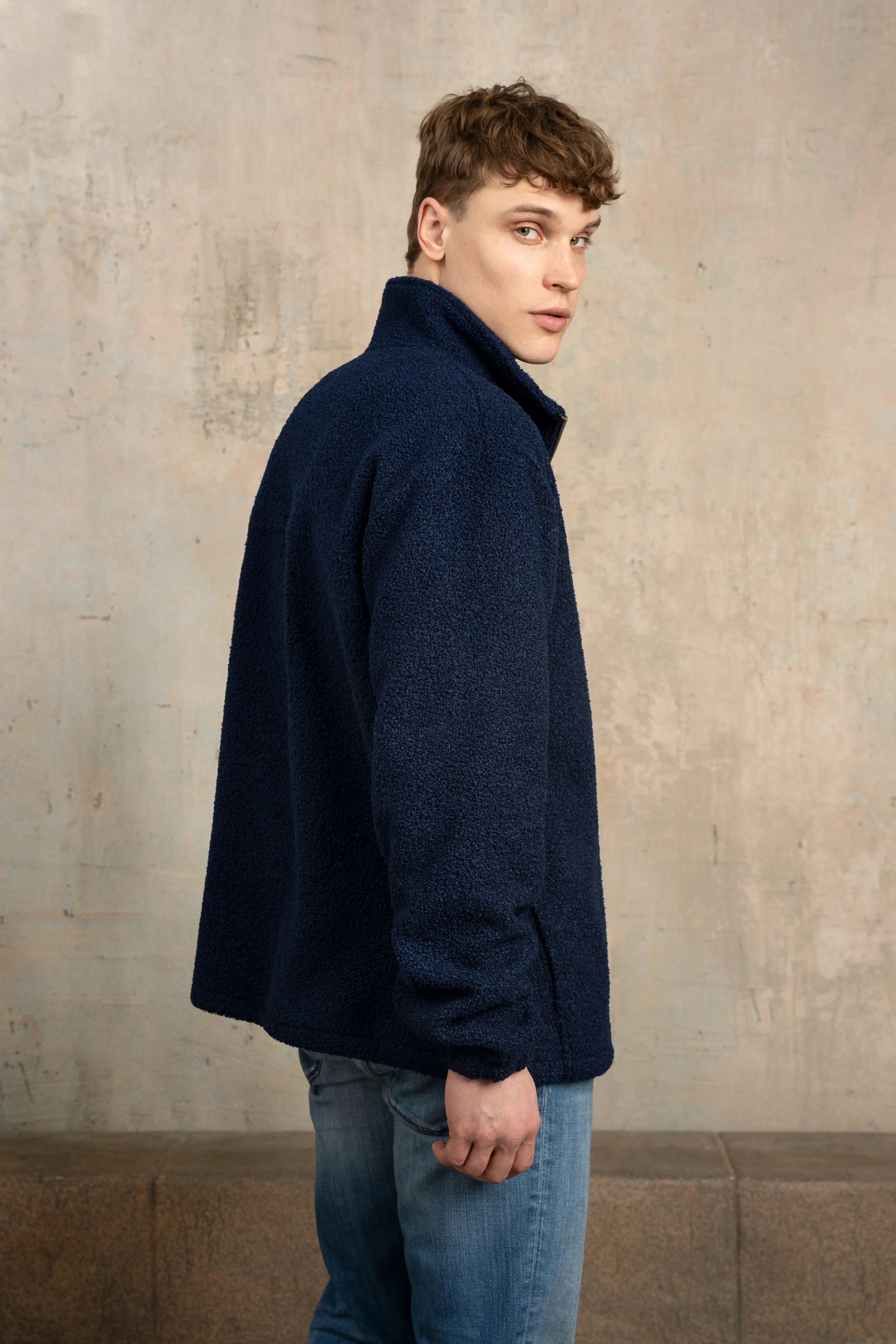 Tamsiai mėlynos spalvos vyriškas džemperis su pilno ilgio užtrauktuku, stačia apykakle, ilgomis rankovėmis ir vaizdu iš šono