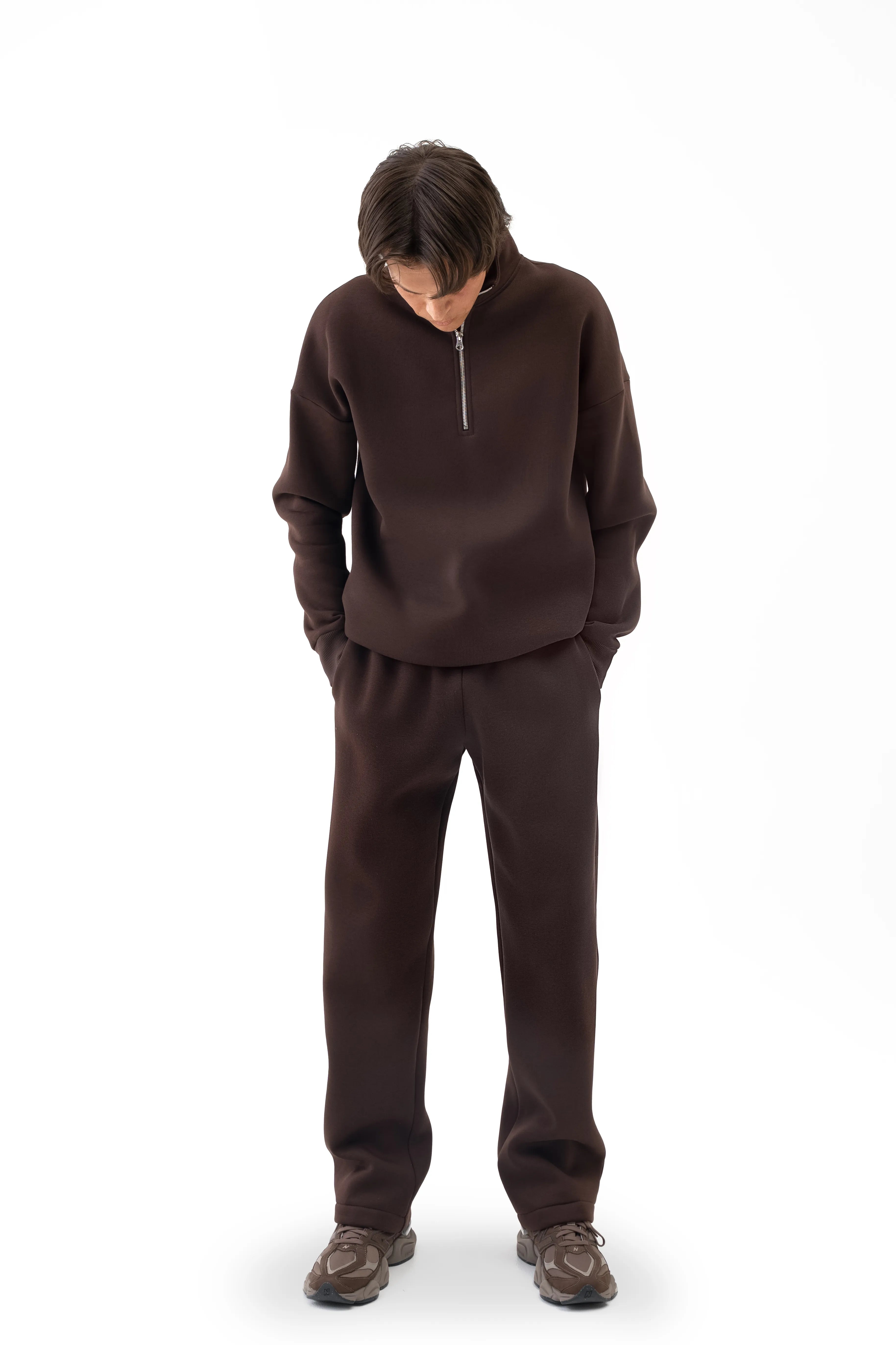 Ein brauner Freizeitanzug für Herren mit gerader Hose und hohem Kragen; das Model blickt nach unten