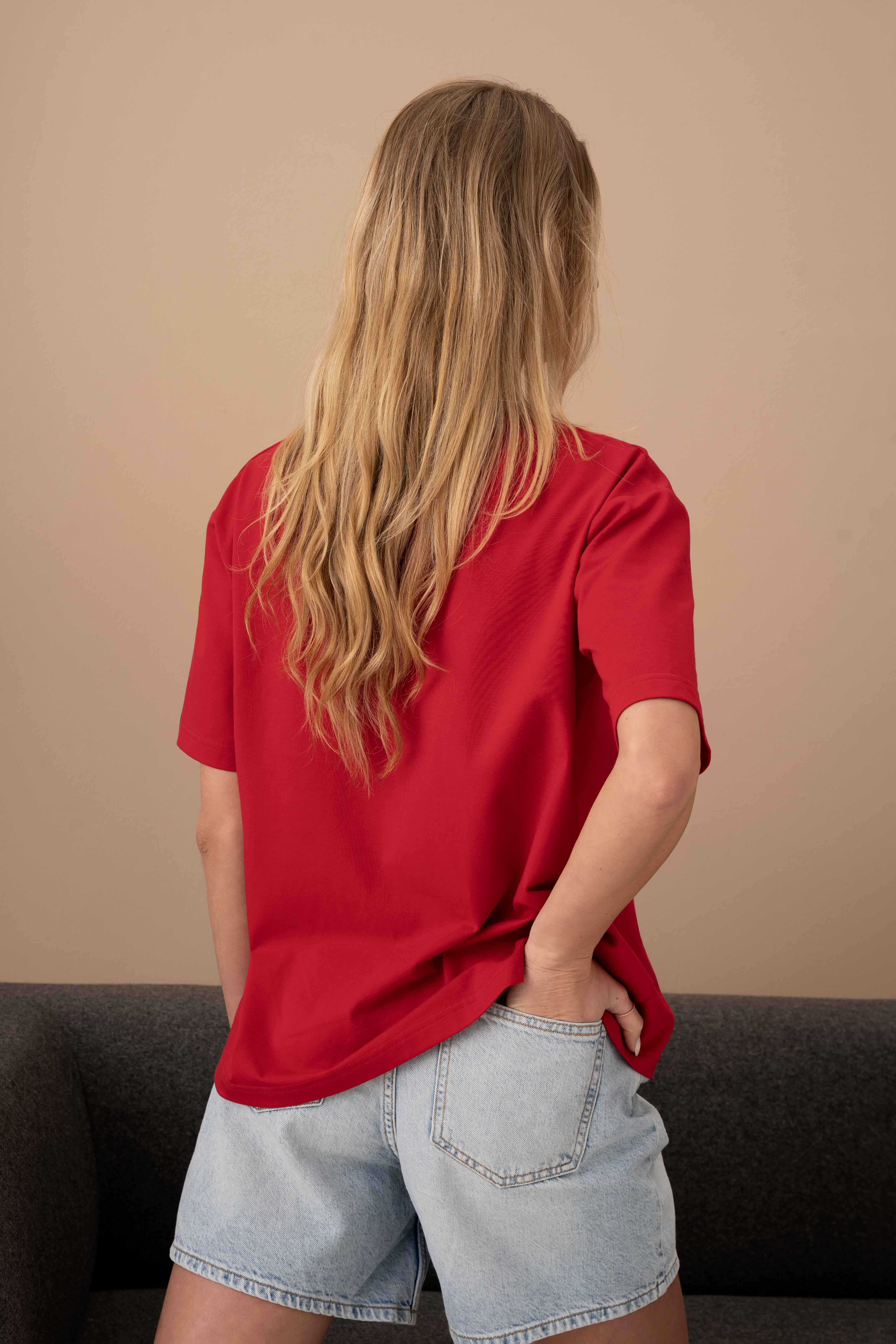modelis su oversized raudonais marškinėliais, demonstruoja marškinėlių nugra