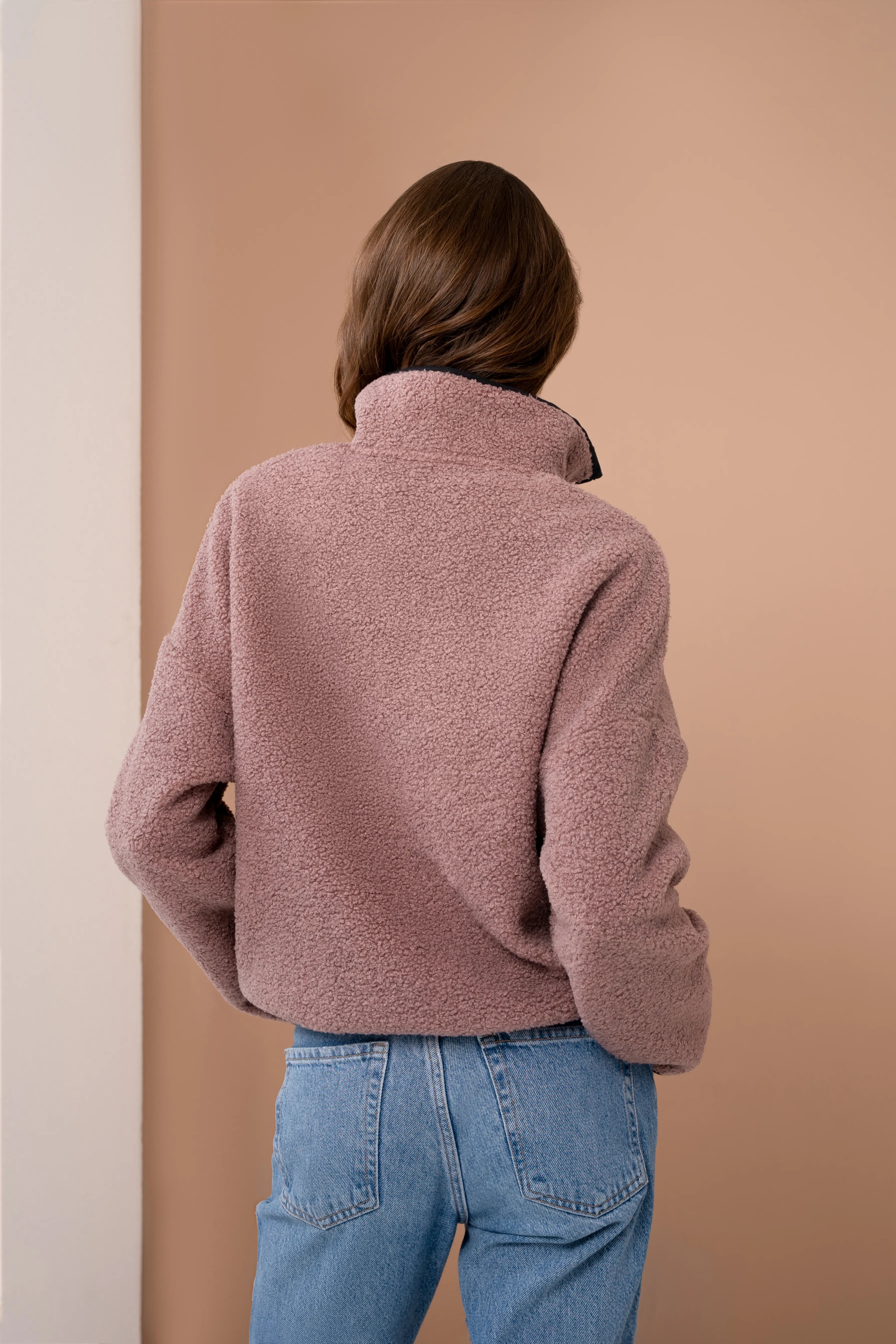 Rausvos spalvos moteriškas džemperis iš nugaros su stačia apykakle, ilgomis rankovėmis ir tiesia nugaros linija