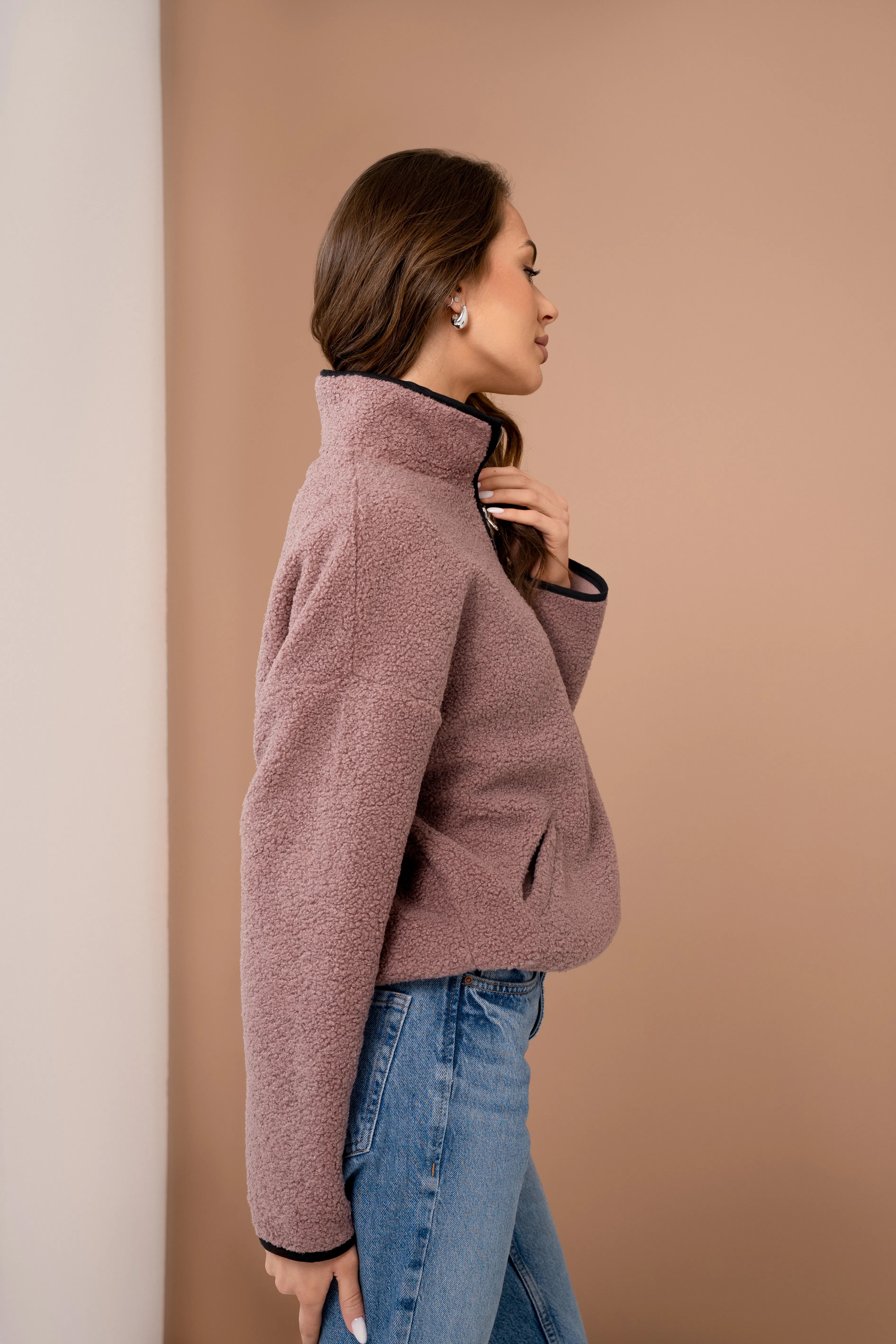Rausvos spalvos moteriškas teddy džemperis su trumpu užtrauktuku, stačia apykakle, ilgomis rankovėmis ir vaizdu iš šono