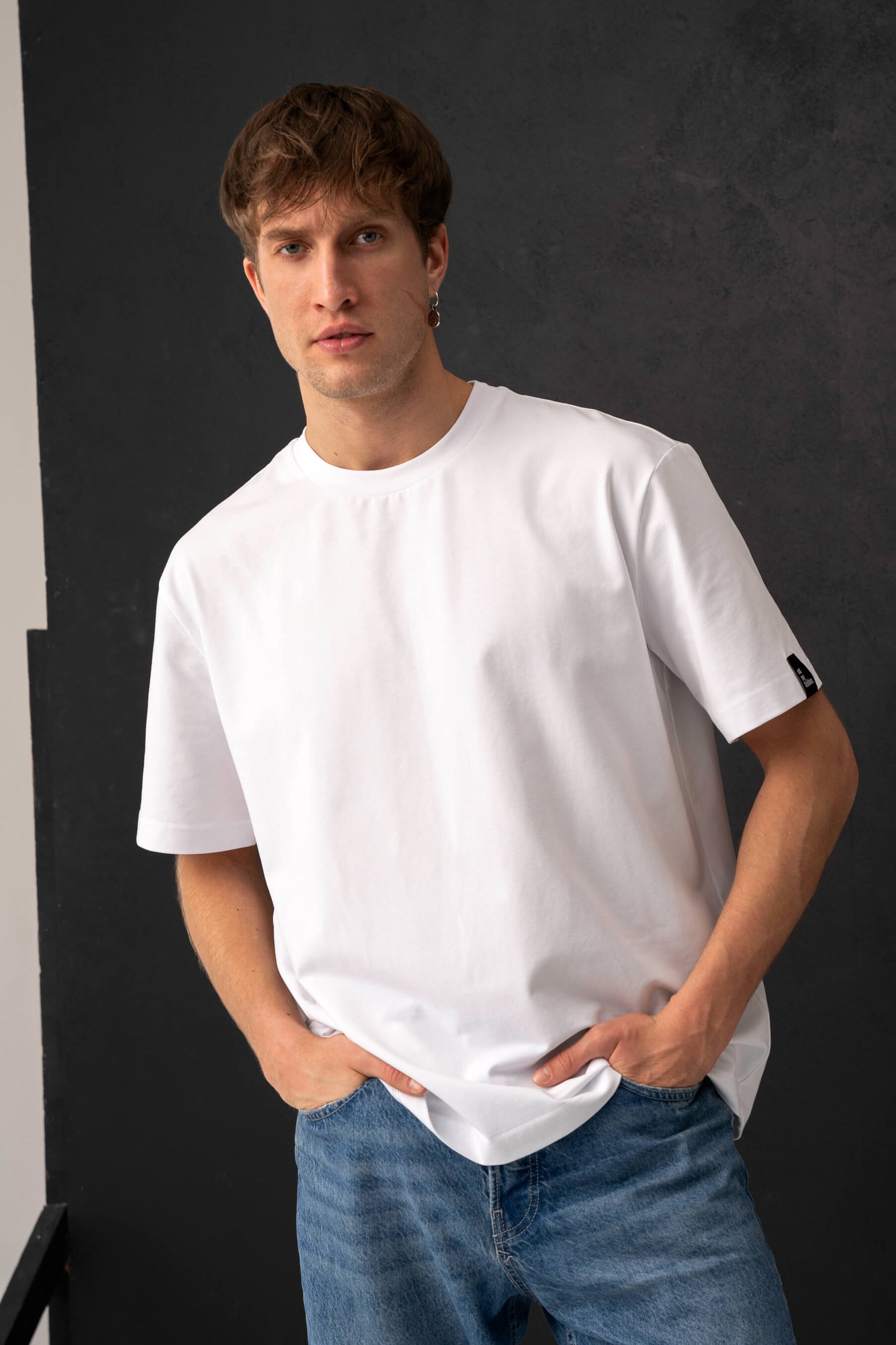 Balti vyriški laisvalaikio marškinėliai iš medvilninio audinio, oversized modelis iš arčiau su džinsais
