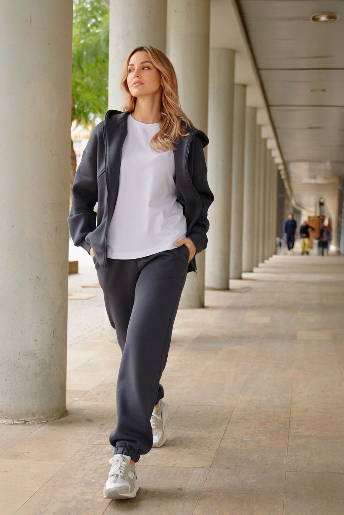 Moteris vilki tamsios spalvos laisvalaikio treningą ir eina miesto aplinkoje