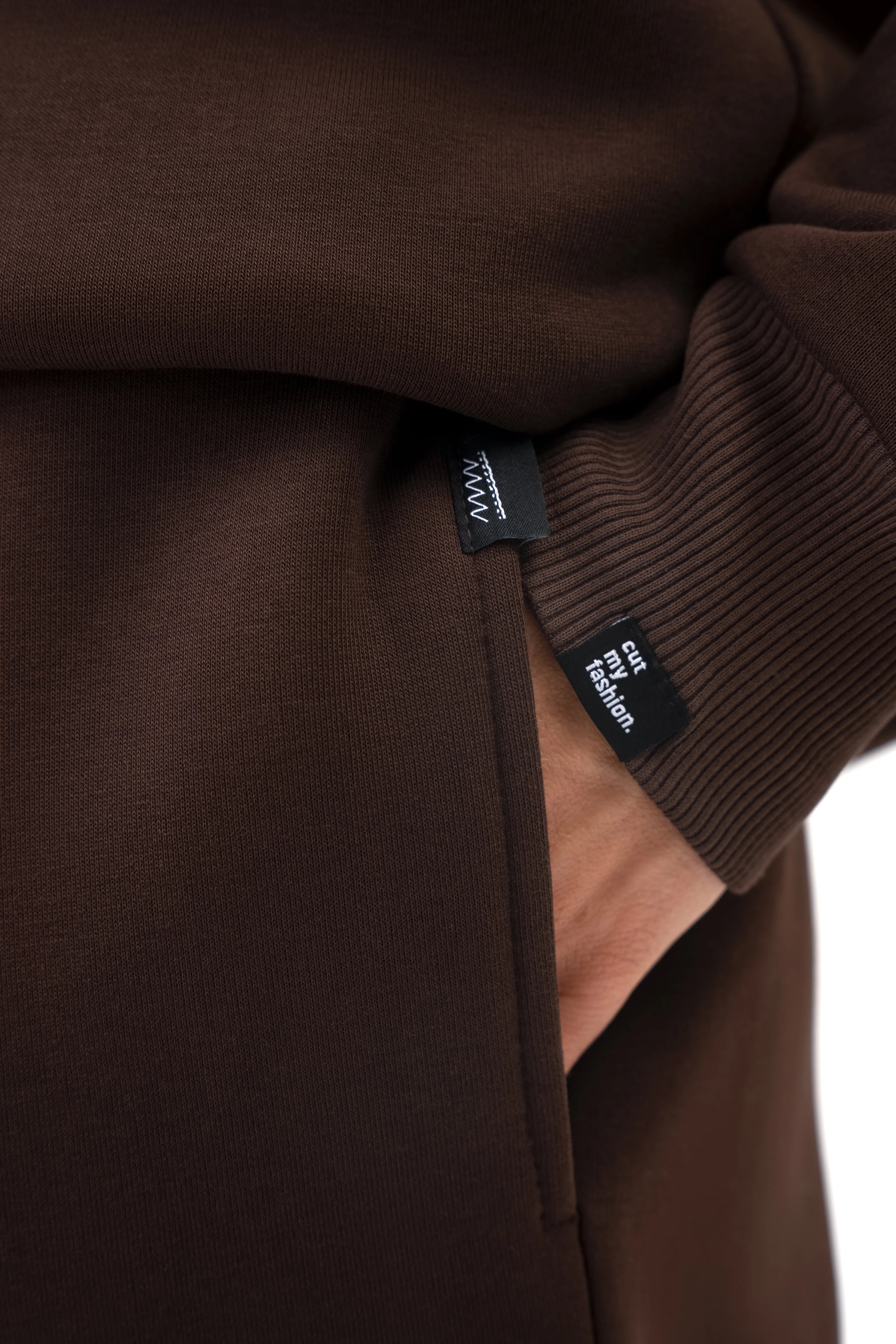 Ein brauner Freizeitanzug für Herren mit Taschen und Manschettenverzierung sowie einem minimalistischen „cutmyfashion“-Etikett
